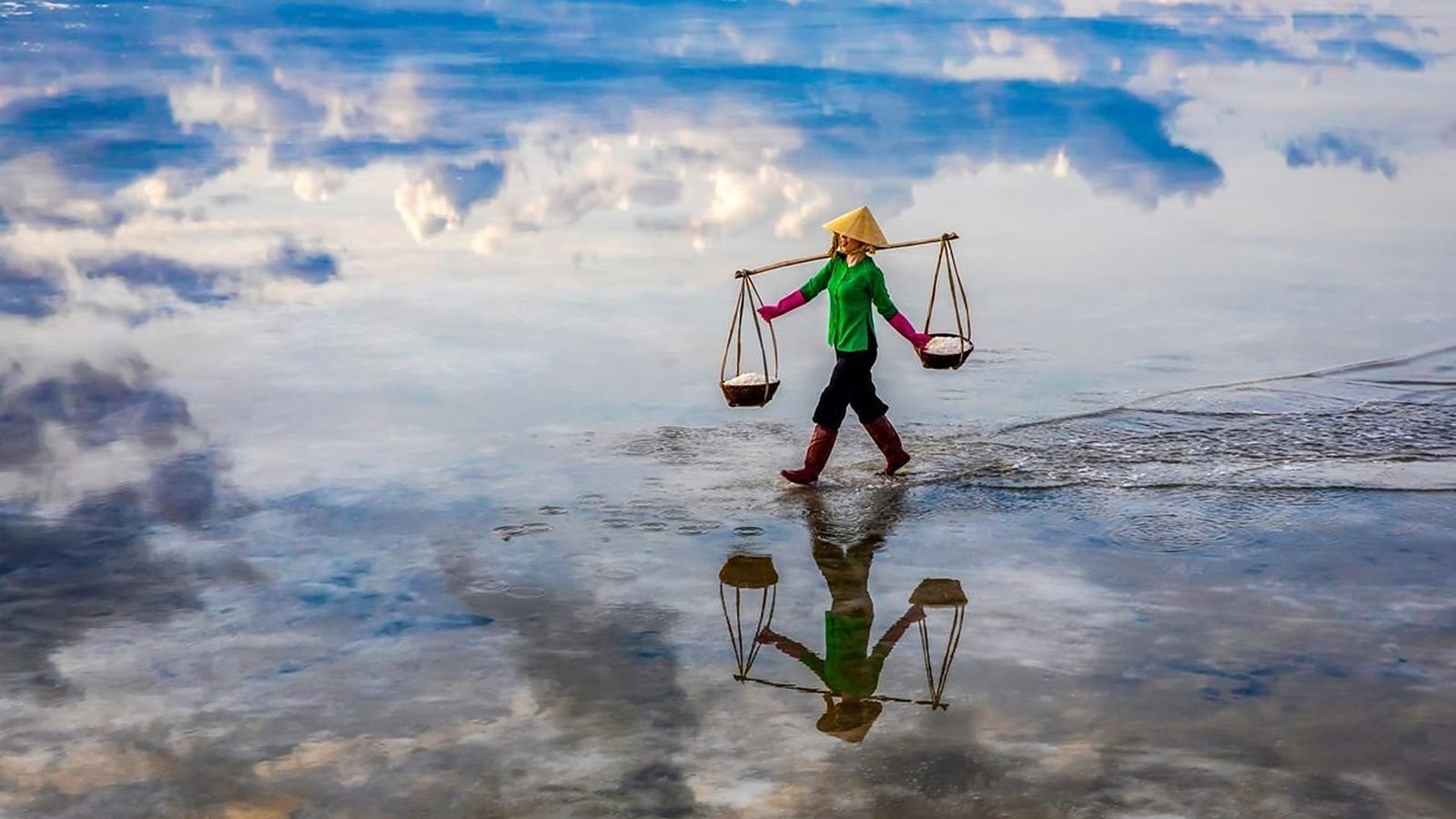Salt harvester walking across a mirror-like salt flat